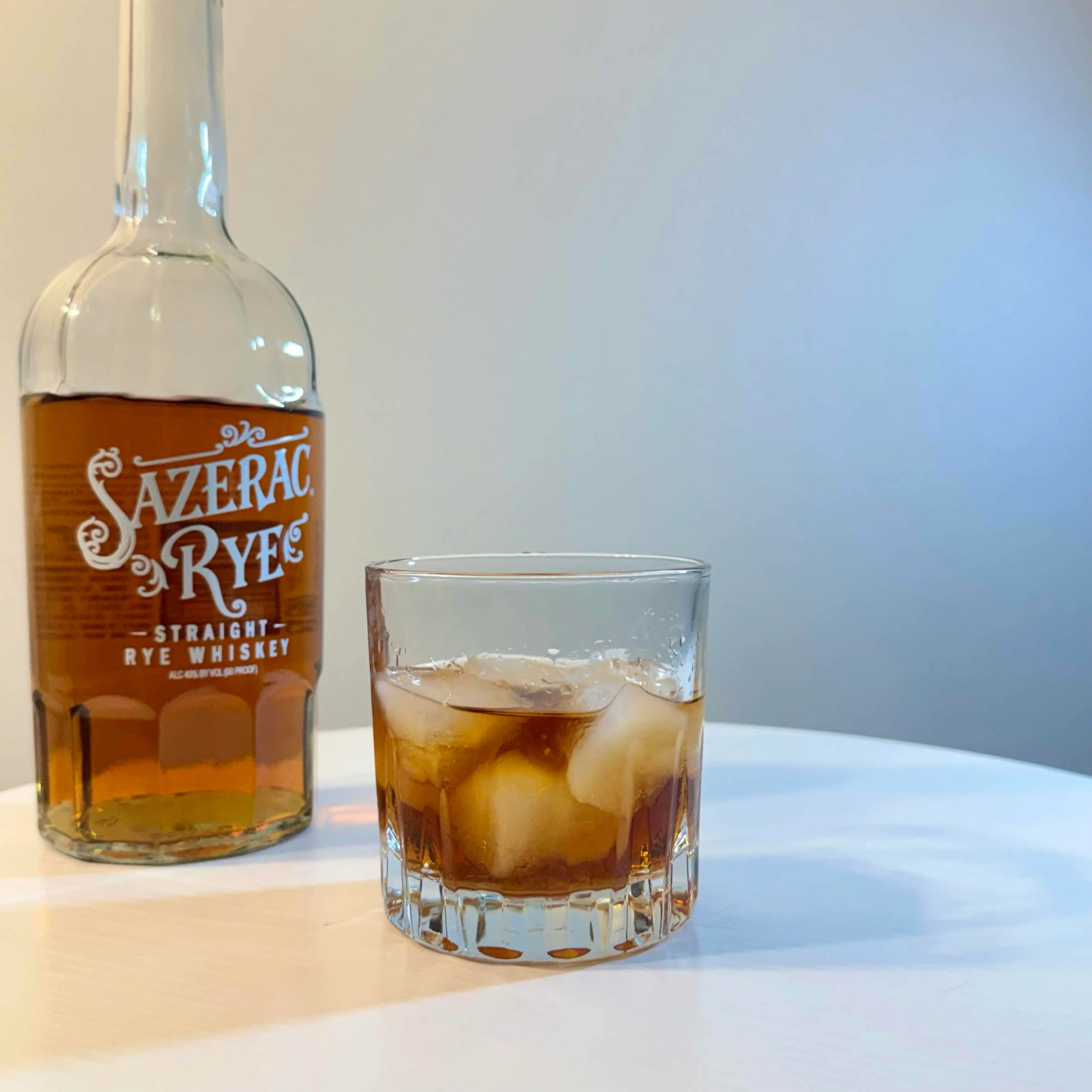 Carajillo Old Fashioned served over ice in a rocks glass beside a bottle of Sazerac rye whiskey